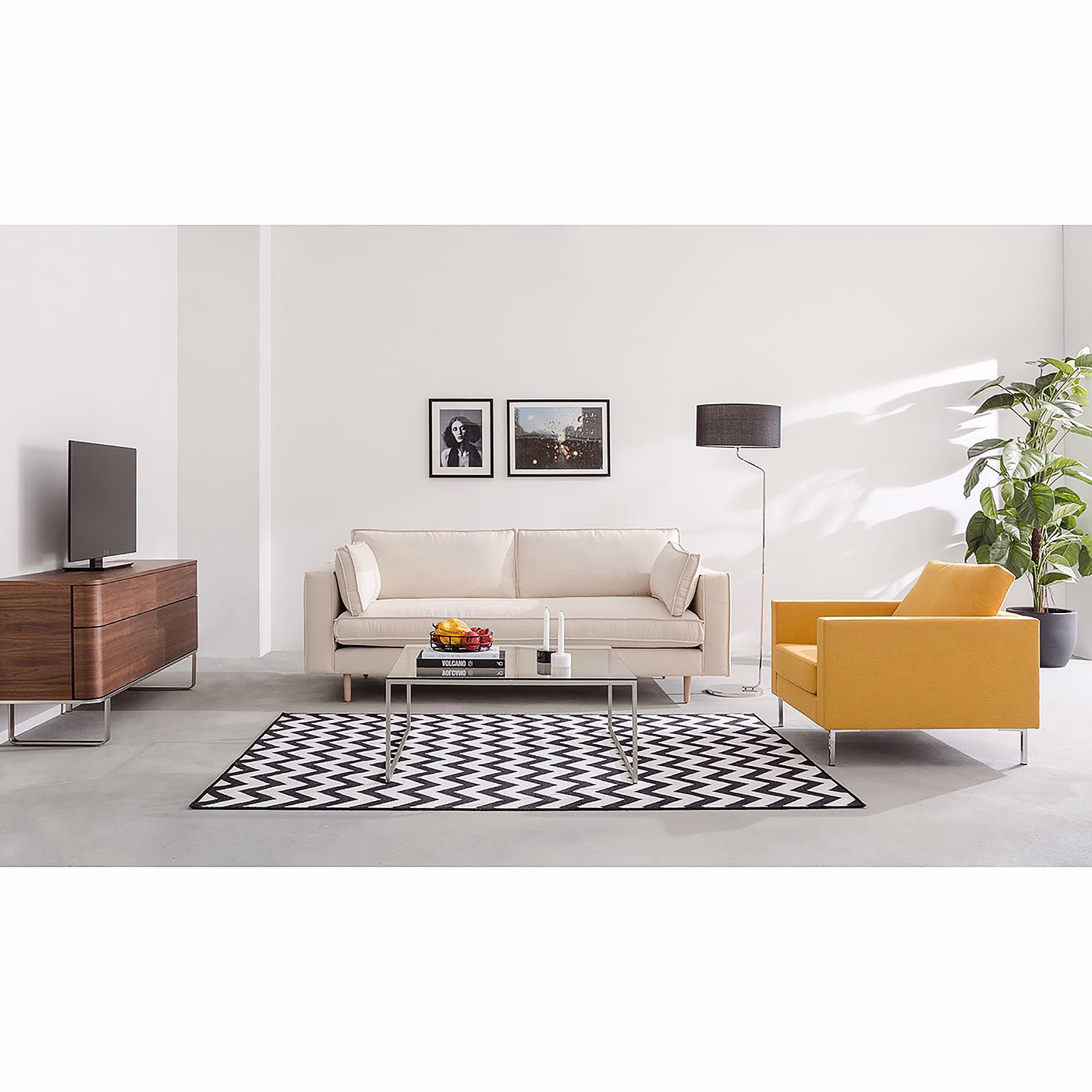 A light-colored sofa and a bright yellow chair sit on a patterned rug in a modern, minimalist living room.