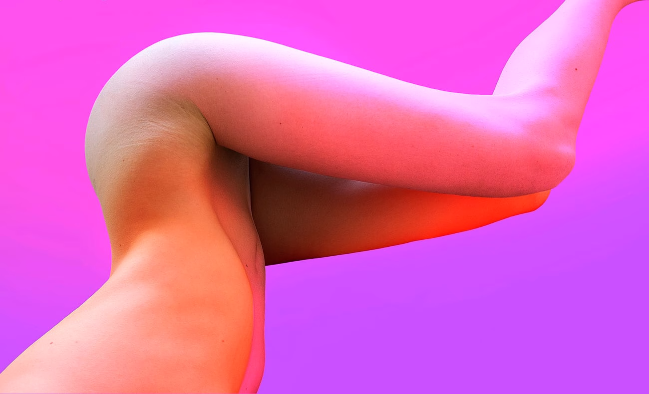 A close-up of a leg bent at the knee, set against a vivid pink background that creates a soft gradient.