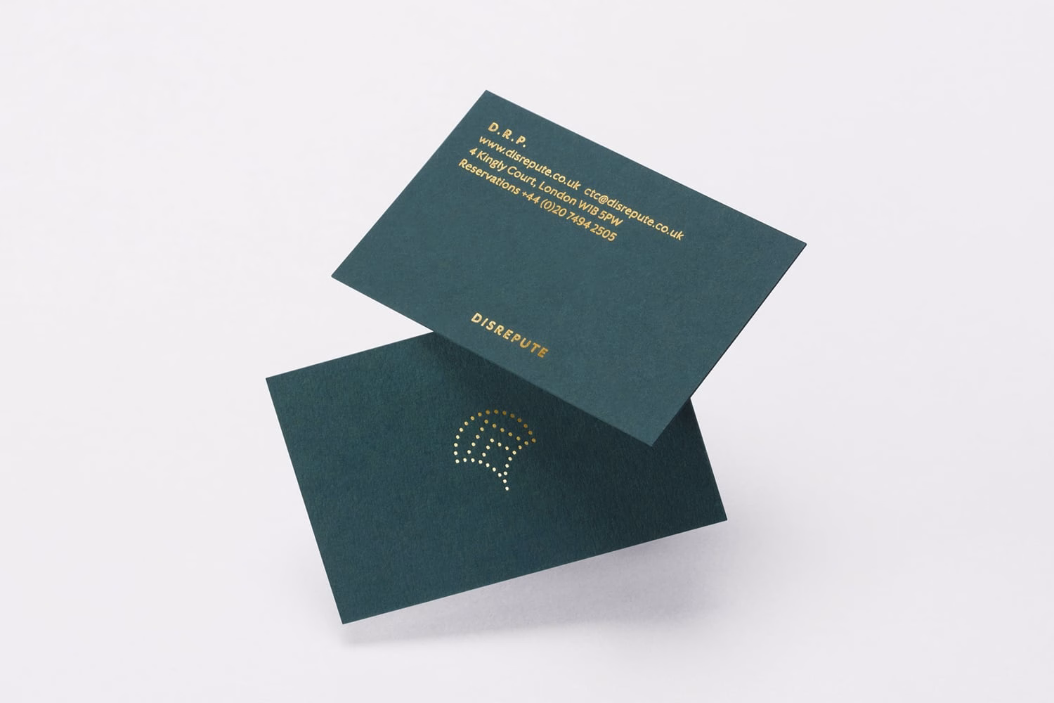 A dark green business card with gold text and a dotted design, layered at an angle on a white background.