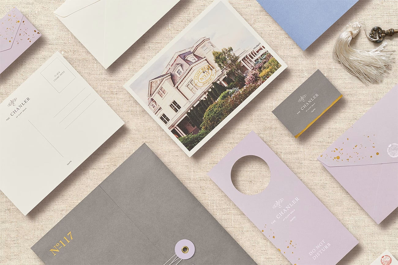 A flat lay of various stationery items, including a postcard and envelopes in muted colors on a textured background.
