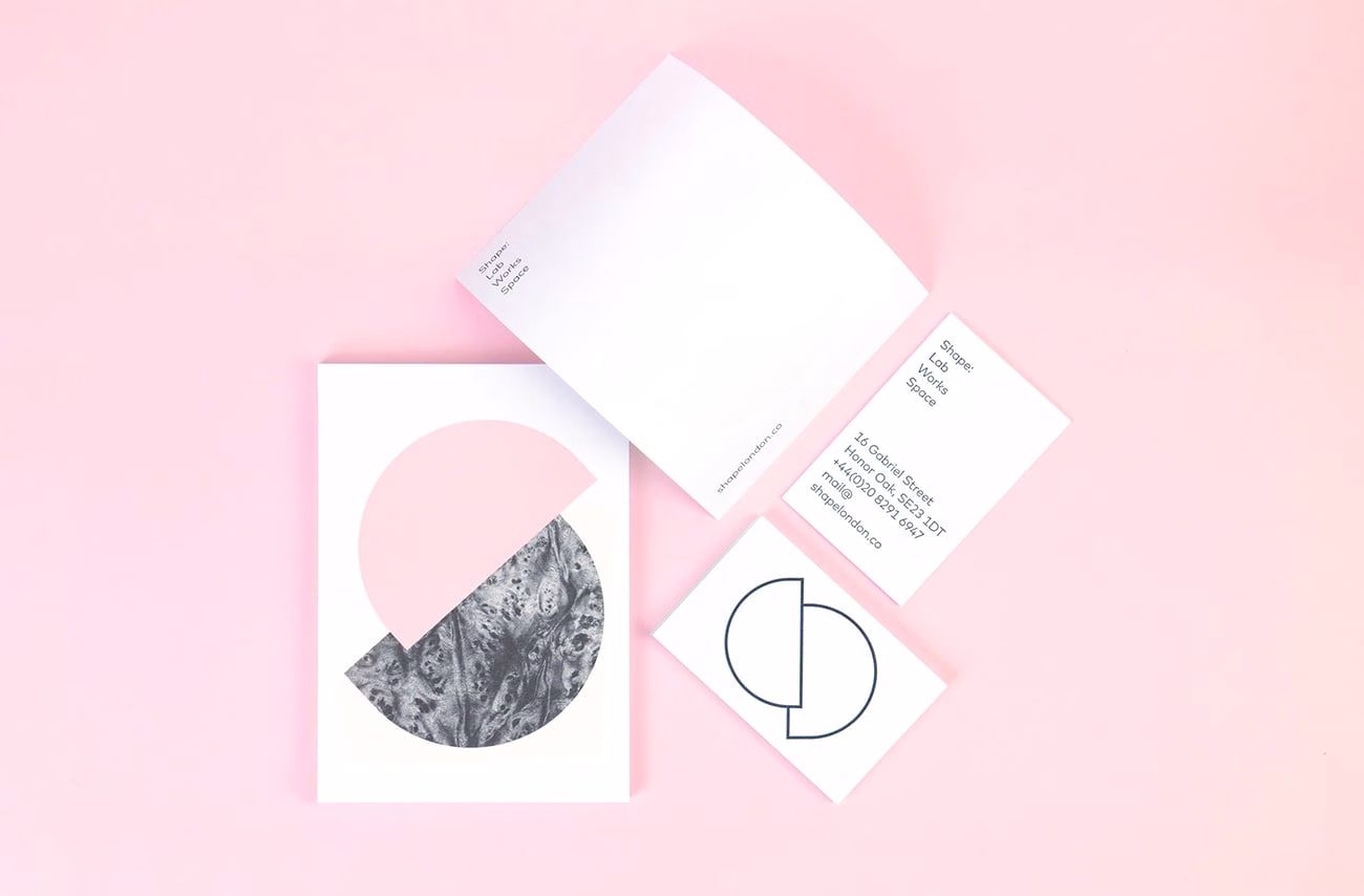 A collection of business cards and a folded brochure on a soft pink background, featuring geometric design elements.