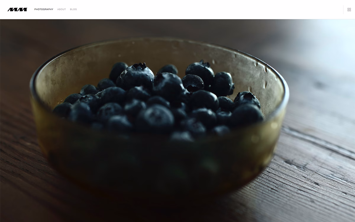 A close-up of a bowl filled with fresh blueberries, resting on a rustic wooden surface.