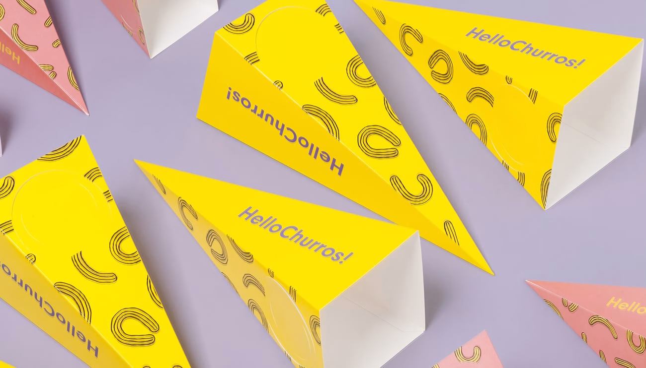 A collection of yellow and pink cone-shaped boxes with playful typography and swirl patterns on a lilac background.