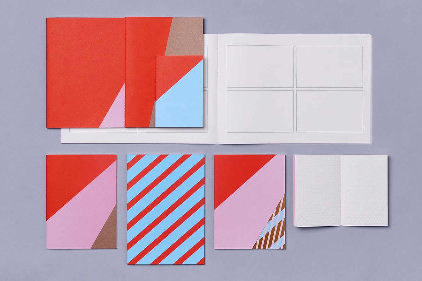 A collection of notebooks and cards in vibrant red, blue, and pink, arranged on a soft gray background.