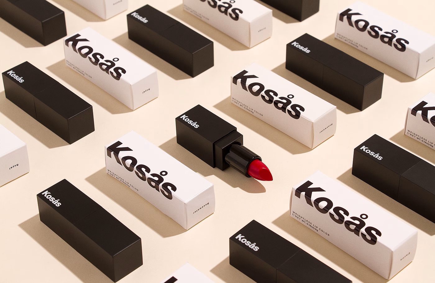 A bold red lipstick rests atop a patterned arrangement of black and white packaging, showcasing minimalist design.