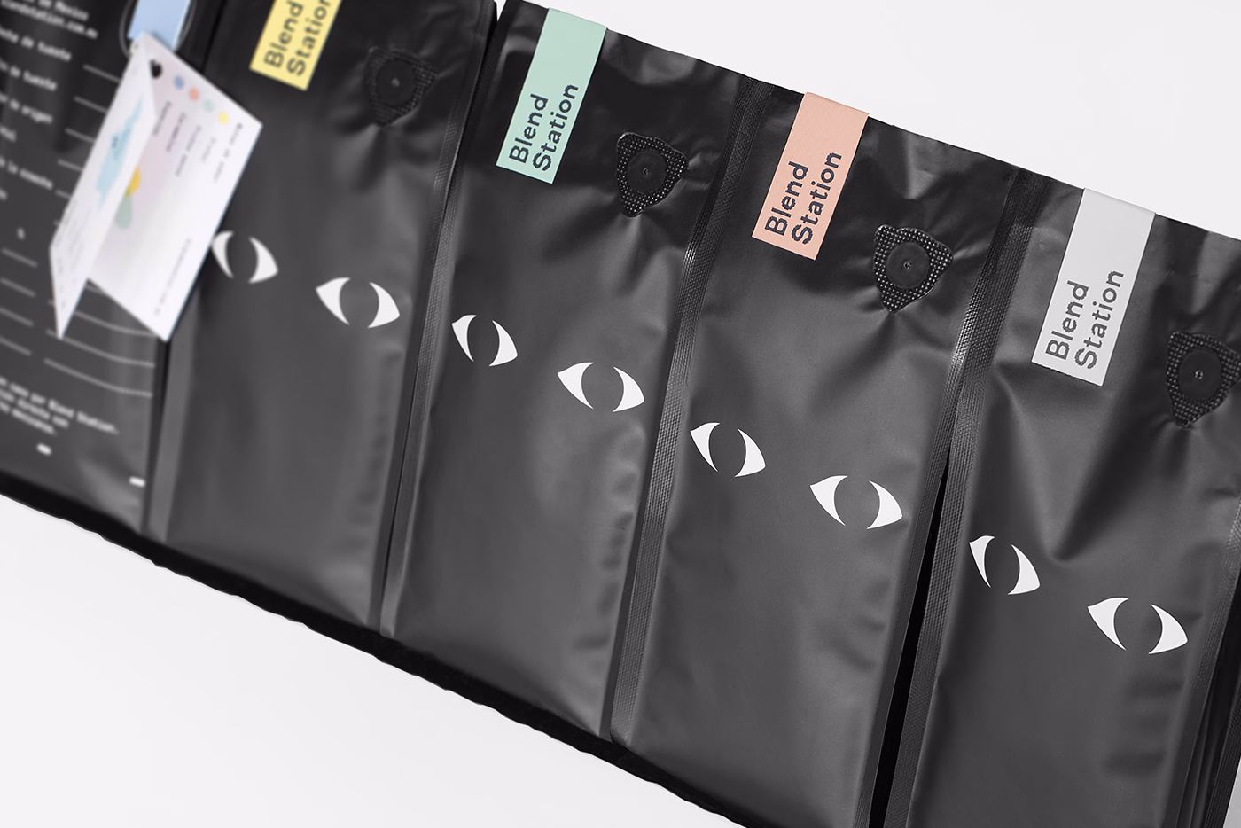 Several black coffee bags are displayed with various colored labels and graphic eye designs.