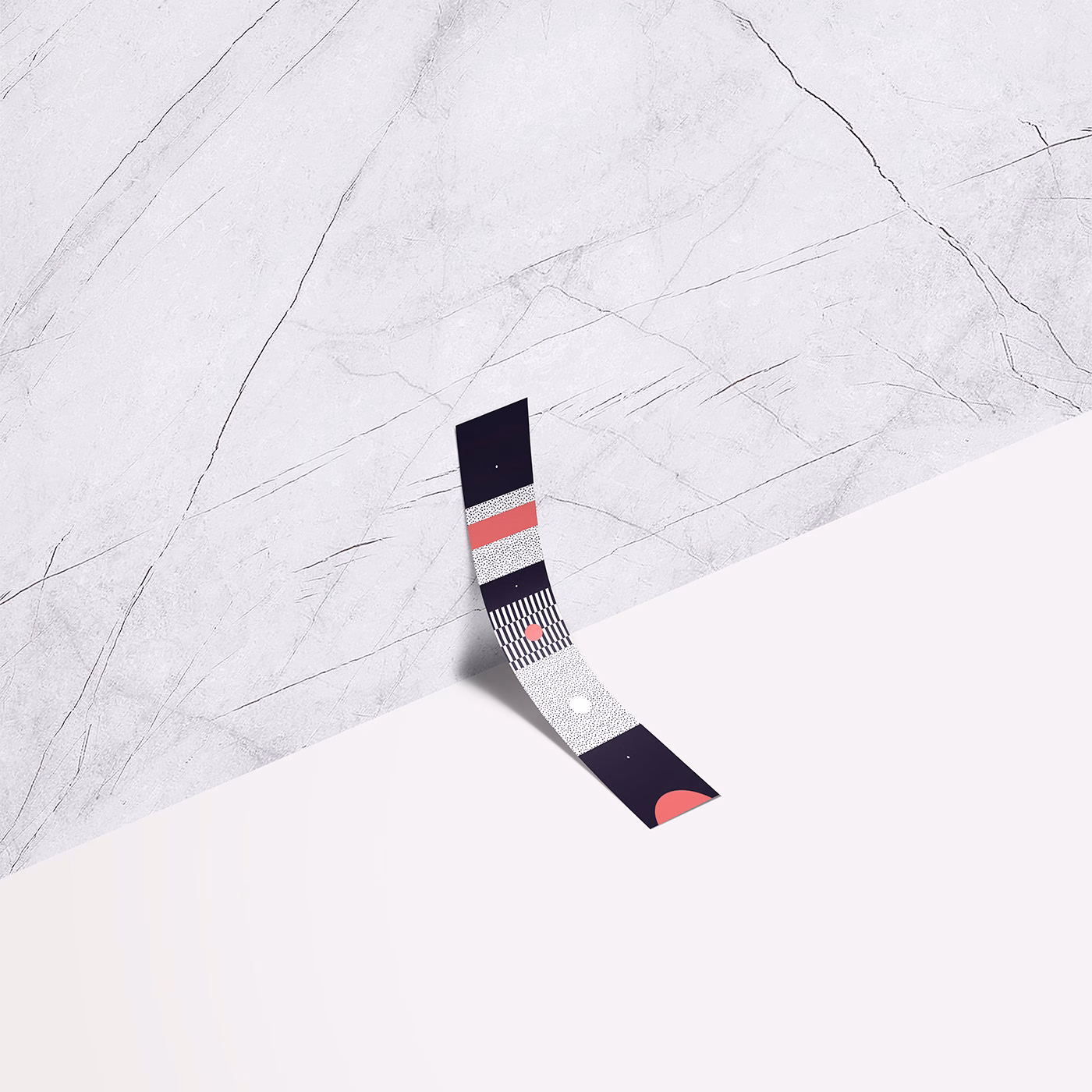 A curved strip with geometric patterns lies on a textured white surface, contrasting the smooth background.