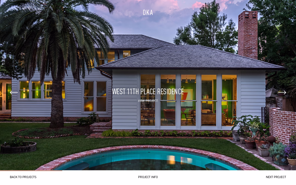 A modern residence with large windows, surrounded by palm trees and a circular pool, under a colorful evening sky.