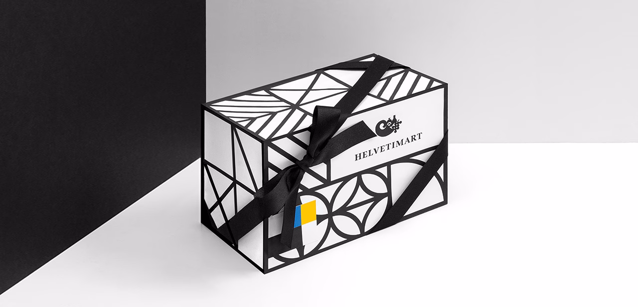 A geometric black and white gift box features a black ribbon and a small blue and yellow accent on one side.