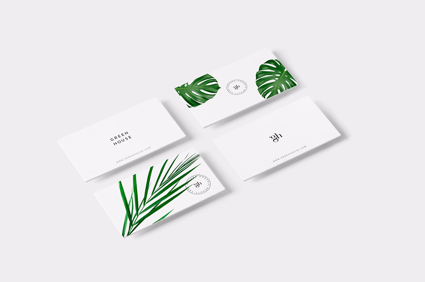 A collection of four business cards featuring green leaf designs on a clean white background.