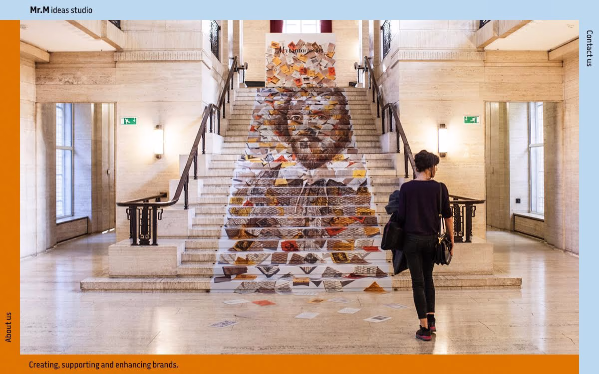 A woman walks down a staircase adorned with colorful patterns and images, set in a bright, modern building.