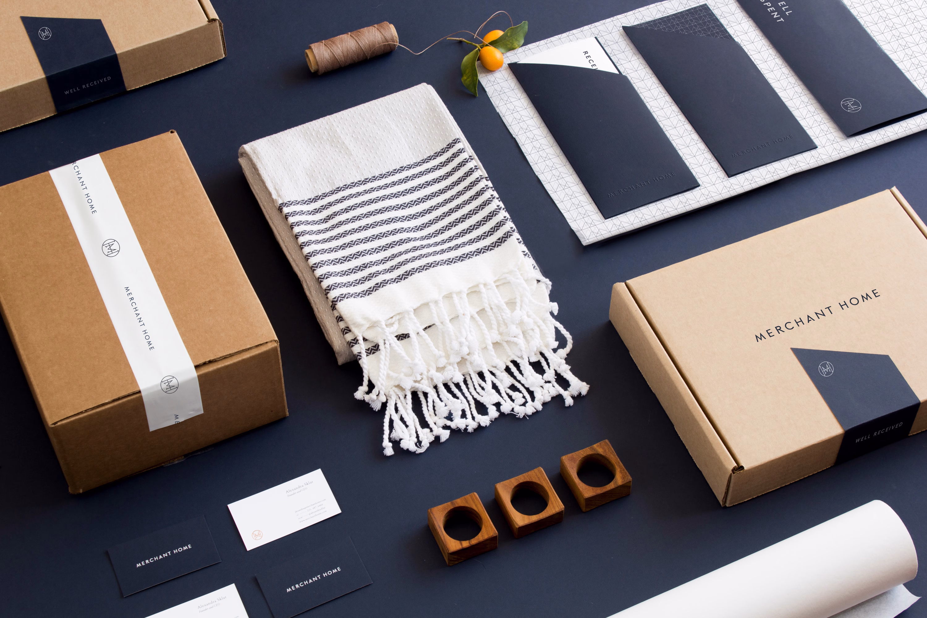 A minimalist arrangement featuring a striped towel, brown boxes, and wooden candle holders on a dark surface.