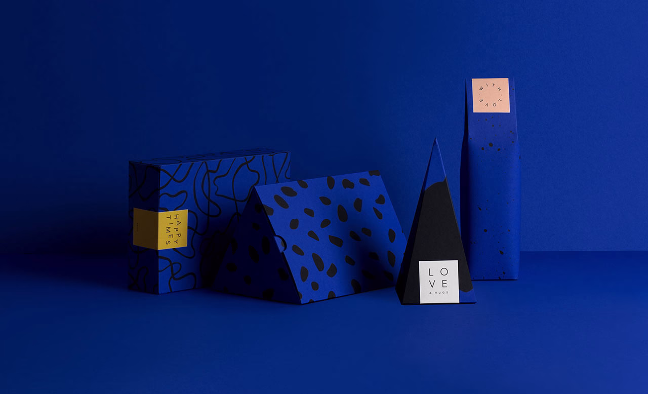 Four blue gift packages with various geometric shapes and black patterns, resting on a blue backdrop.