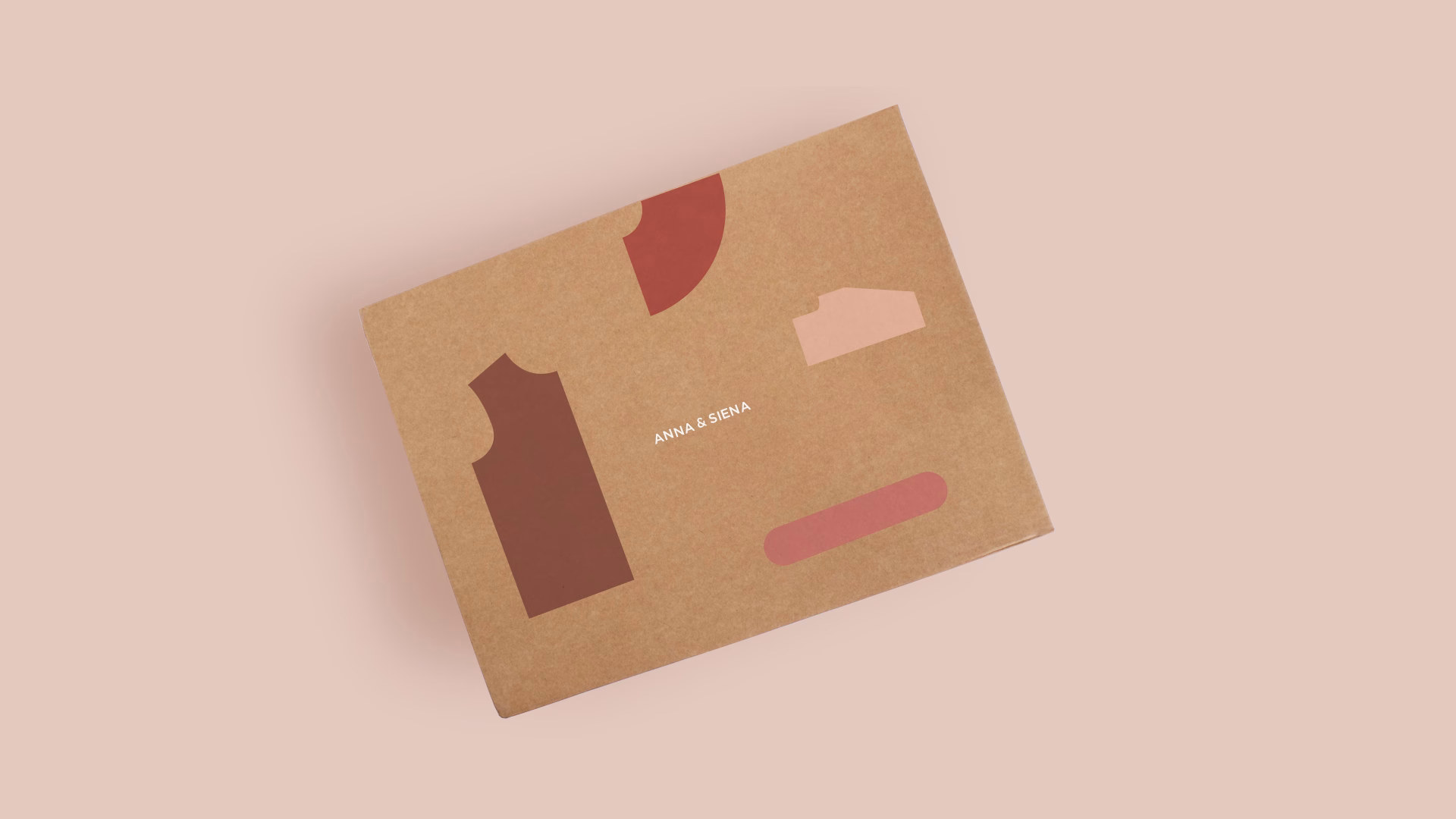 A textured brown box featuring colorful geometric shapes and the text "ANNA & SIENA" centered on a soft pink background.