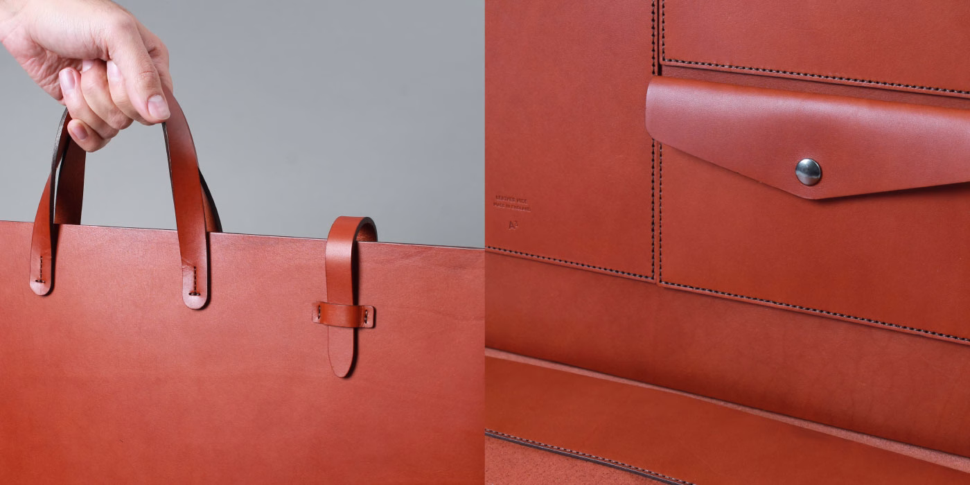 A hand grips a large, smooth brown leather tote bag, revealing its interior with pockets and neat stitching.