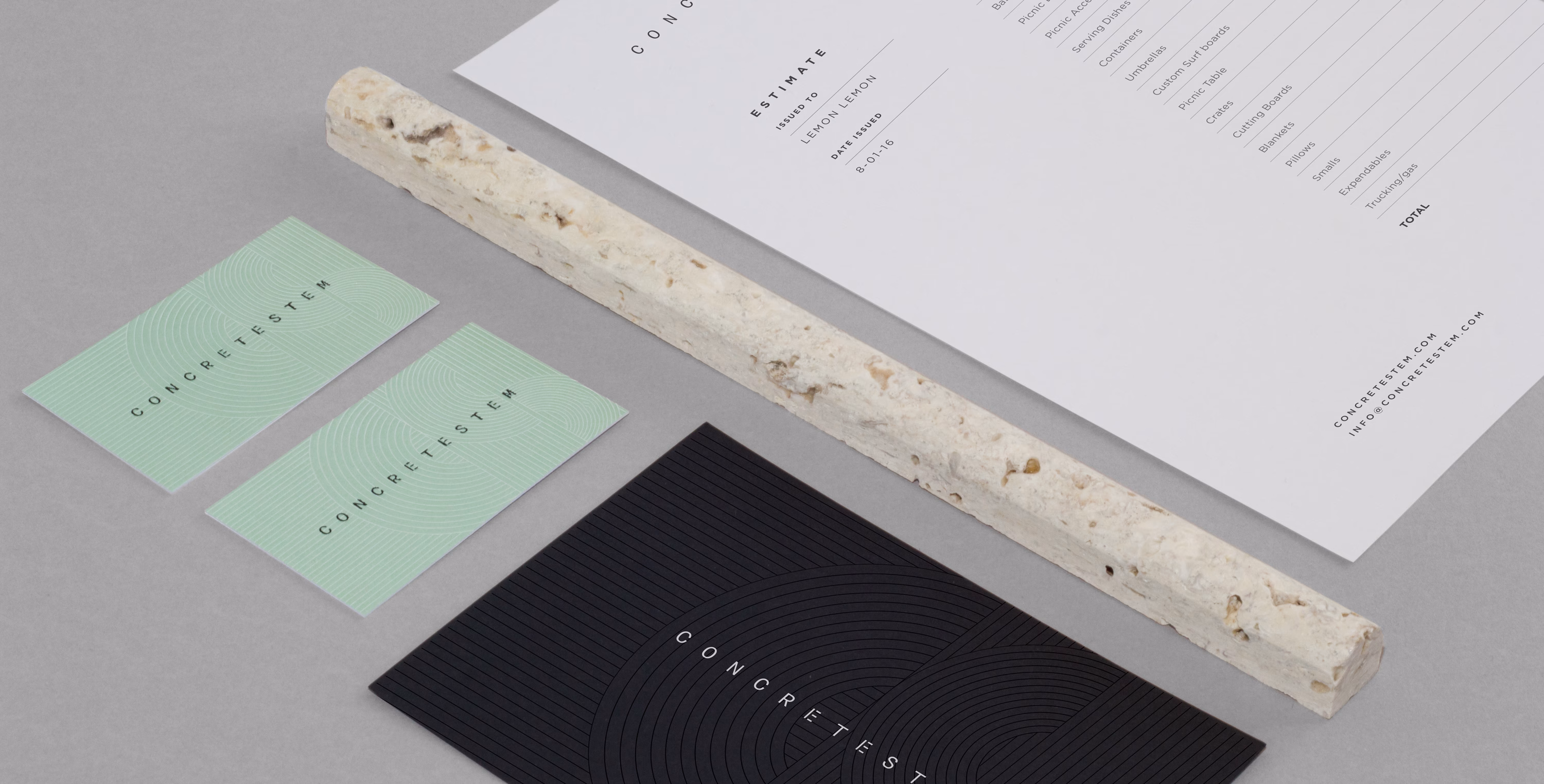 A textured beige rod rests alongside green and black business cards and a white estimate document on a gray surface.