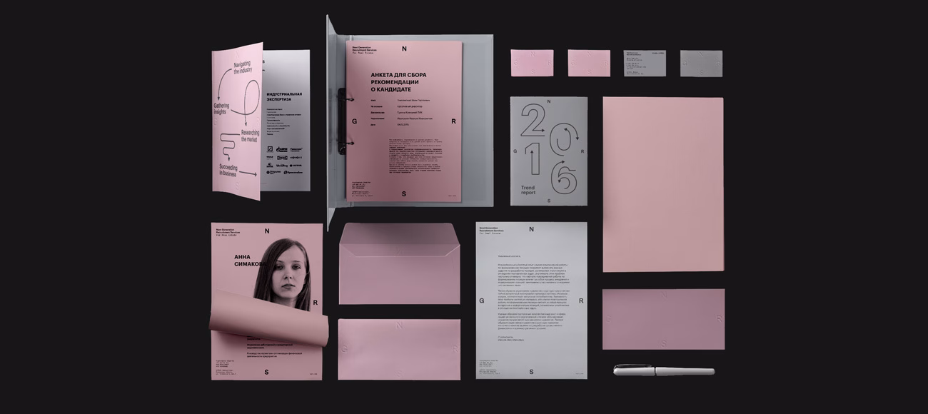 A flat lay of various stationery items in soft pink and gray, including a folder, letters, and business cards.