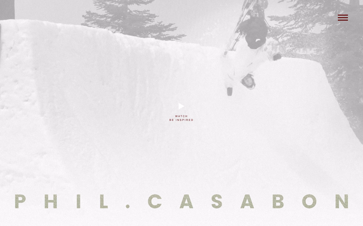 A skier performs a trick off a large snow ramp surrounded by tall trees in a misty landscape. The text appears below.