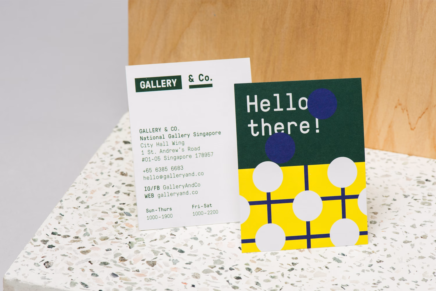 Two business cards are displayed on a textured surface, featuring bold colors and playful geometric patterns.