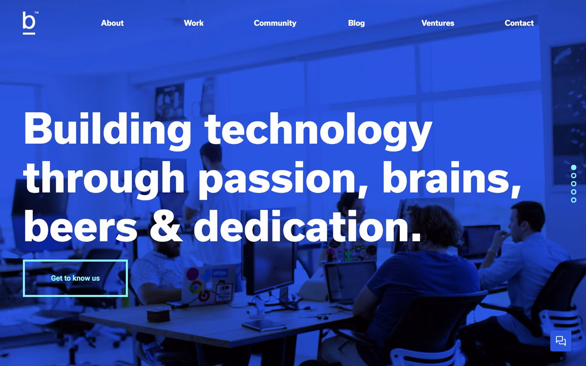 A vibrant blue background features bold, white text promoting teamwork in technology, with visible desks and computers.