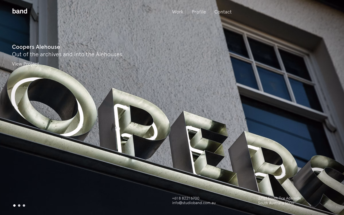 Close-up view of illuminated metal letters spelling "Coopers" on a building exterior, with a lightly textured wall in the background.