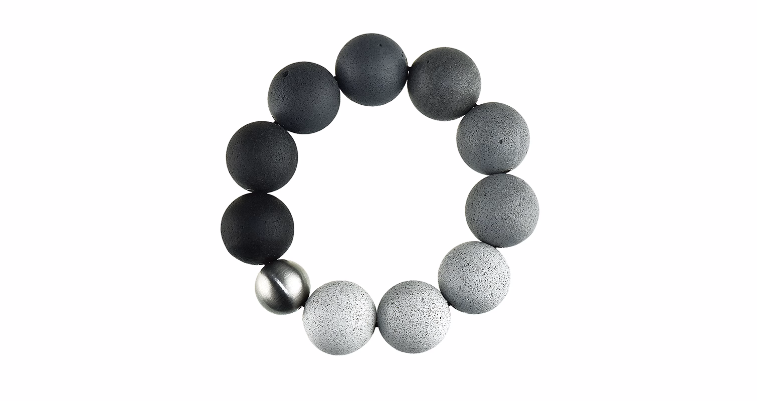 A circular arrangement of spheres in varying shades of grey and black, with one metallic sphere among them.