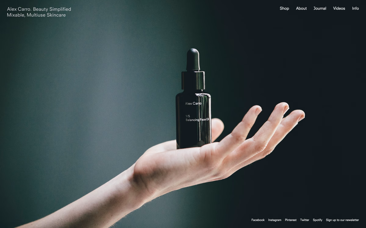 A hand holds a dark glass dropper bottle against a softly blurred dark background.