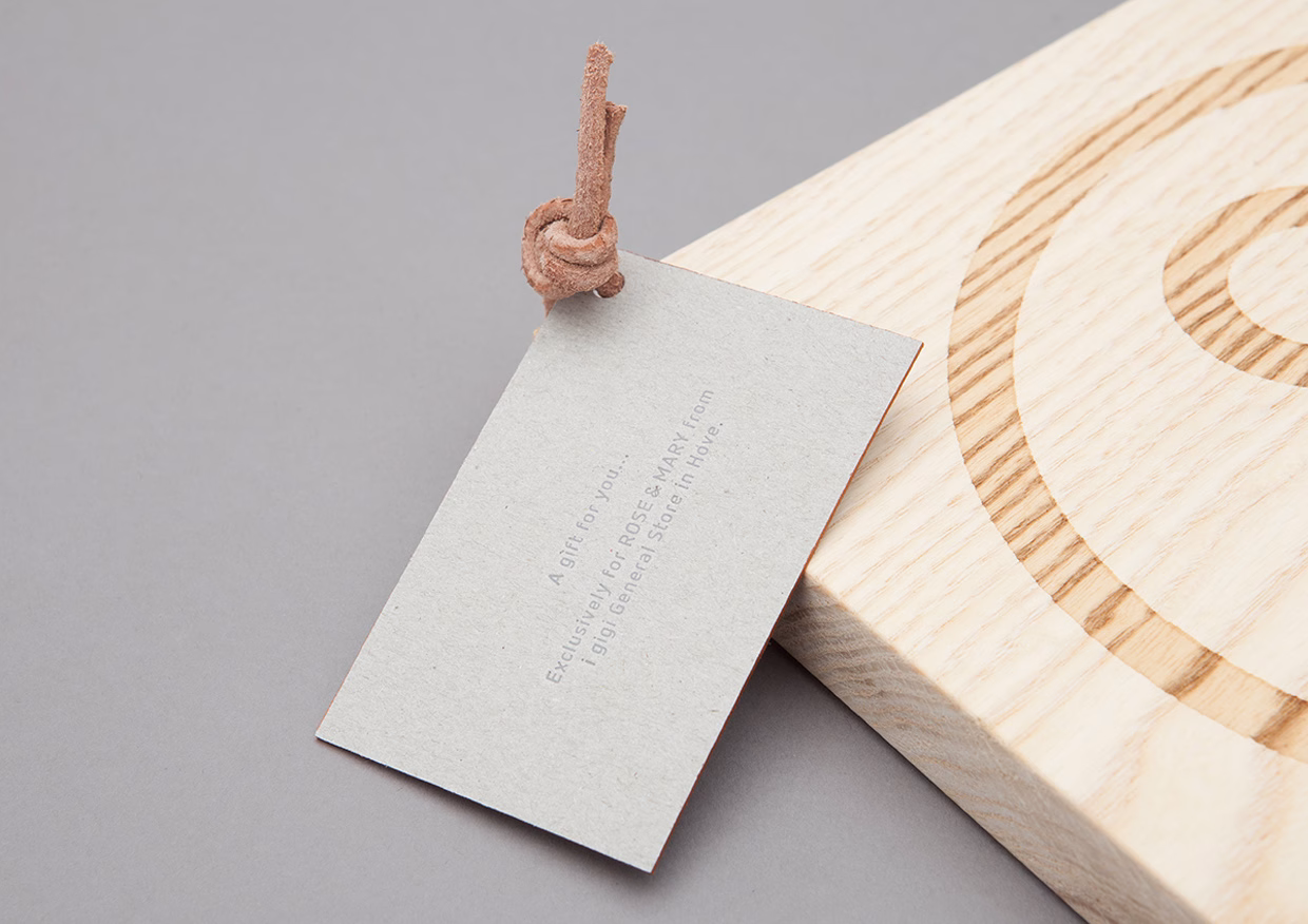 A textured gray card with a leather tie rests on a light wooden surface, showcasing a spiral pattern.