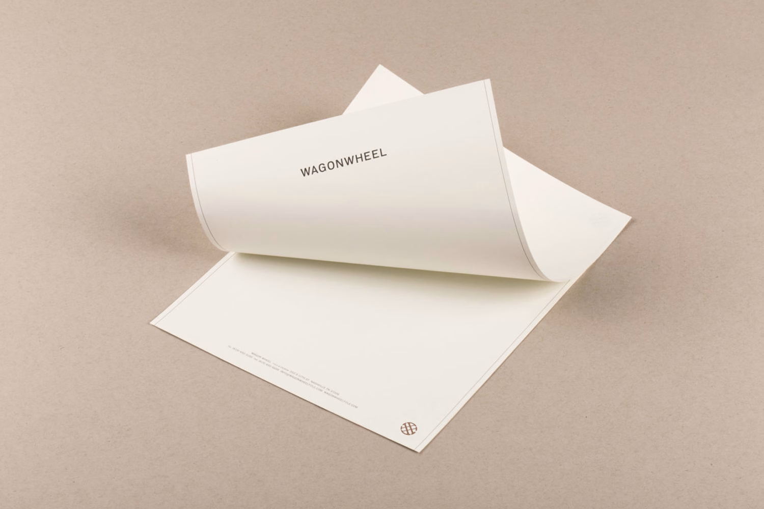 An open, cream-colored sheet of paper features the word "WAGONWHEEL" printed in bold, simple typography.