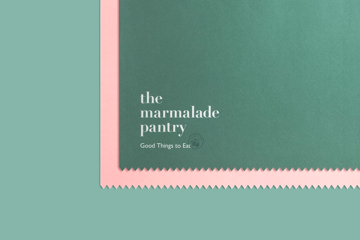A green paper background features the text “the marmalade pantry” in white, complemented by a pink scalloped edge.