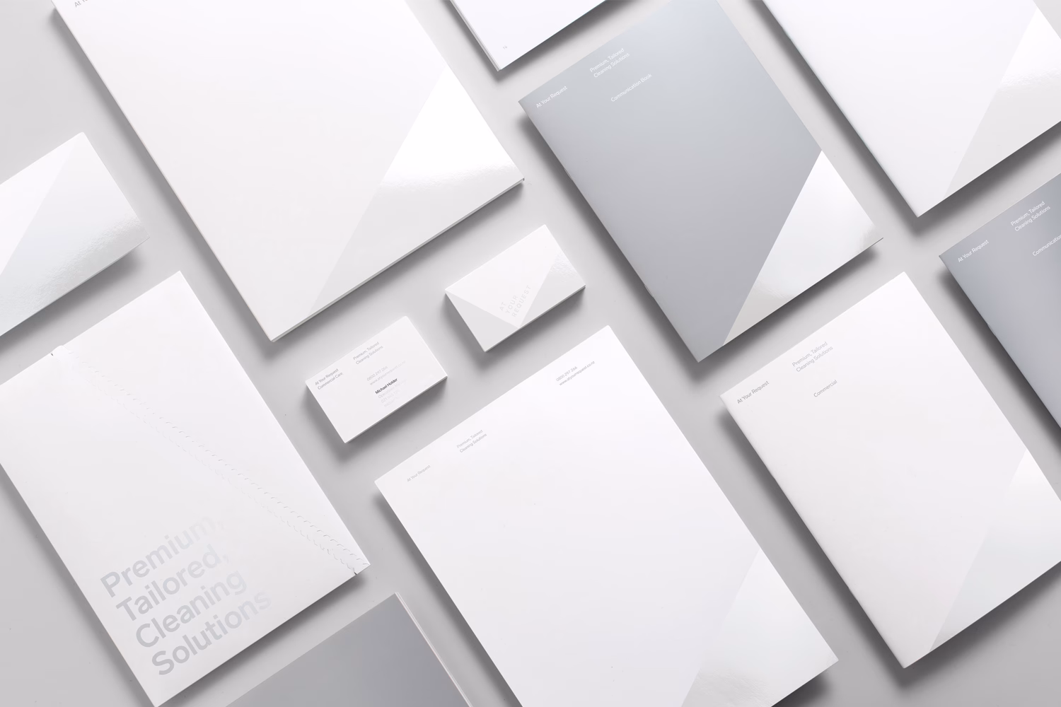 A collection of white and gray stationery, featuring sleek lines and minimalist typography on various paper styles.