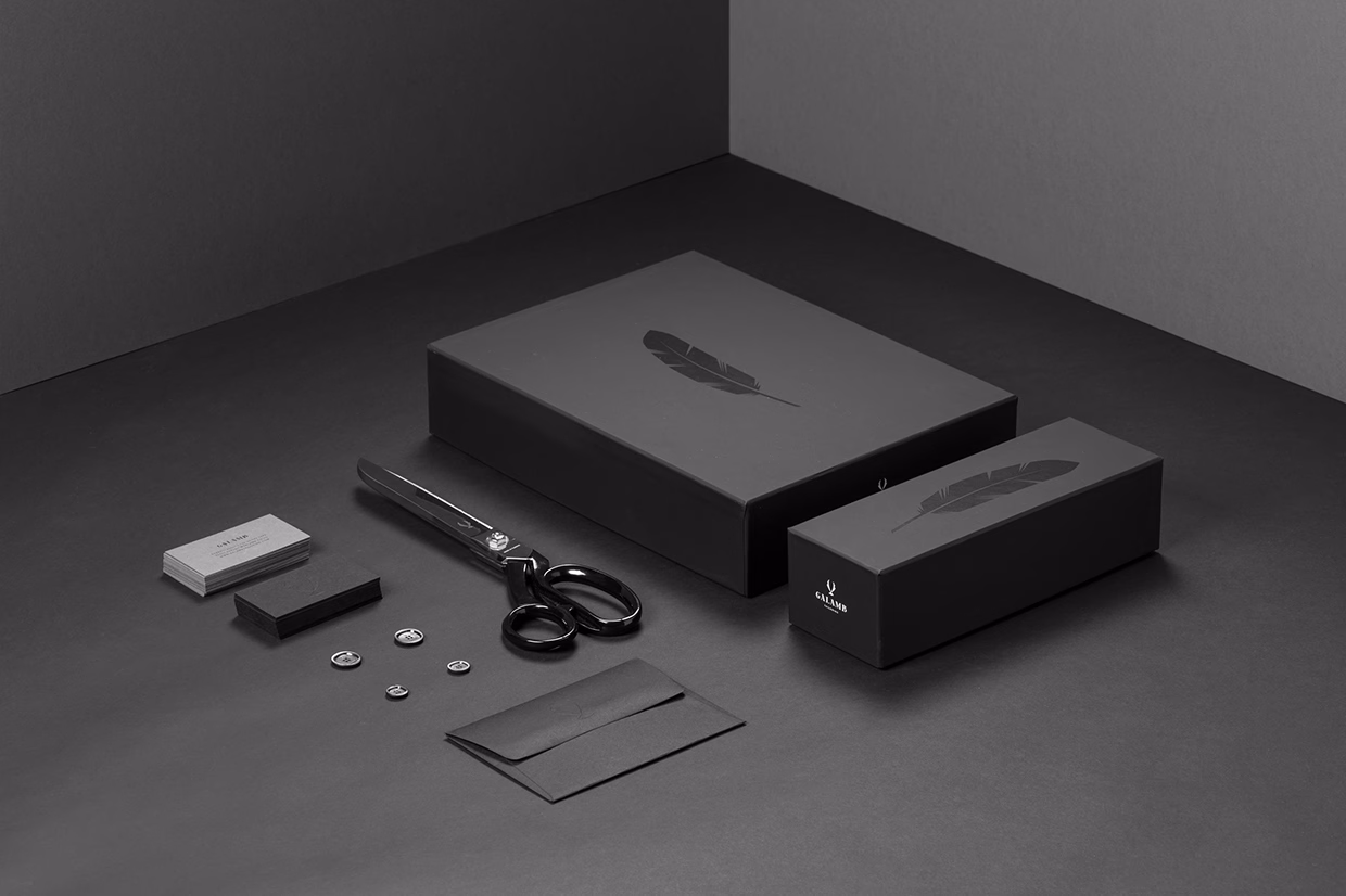 A monochromatic arrangement of black packaging, scissors, and stationery on a dark surface, emphasizing minimalist design.
