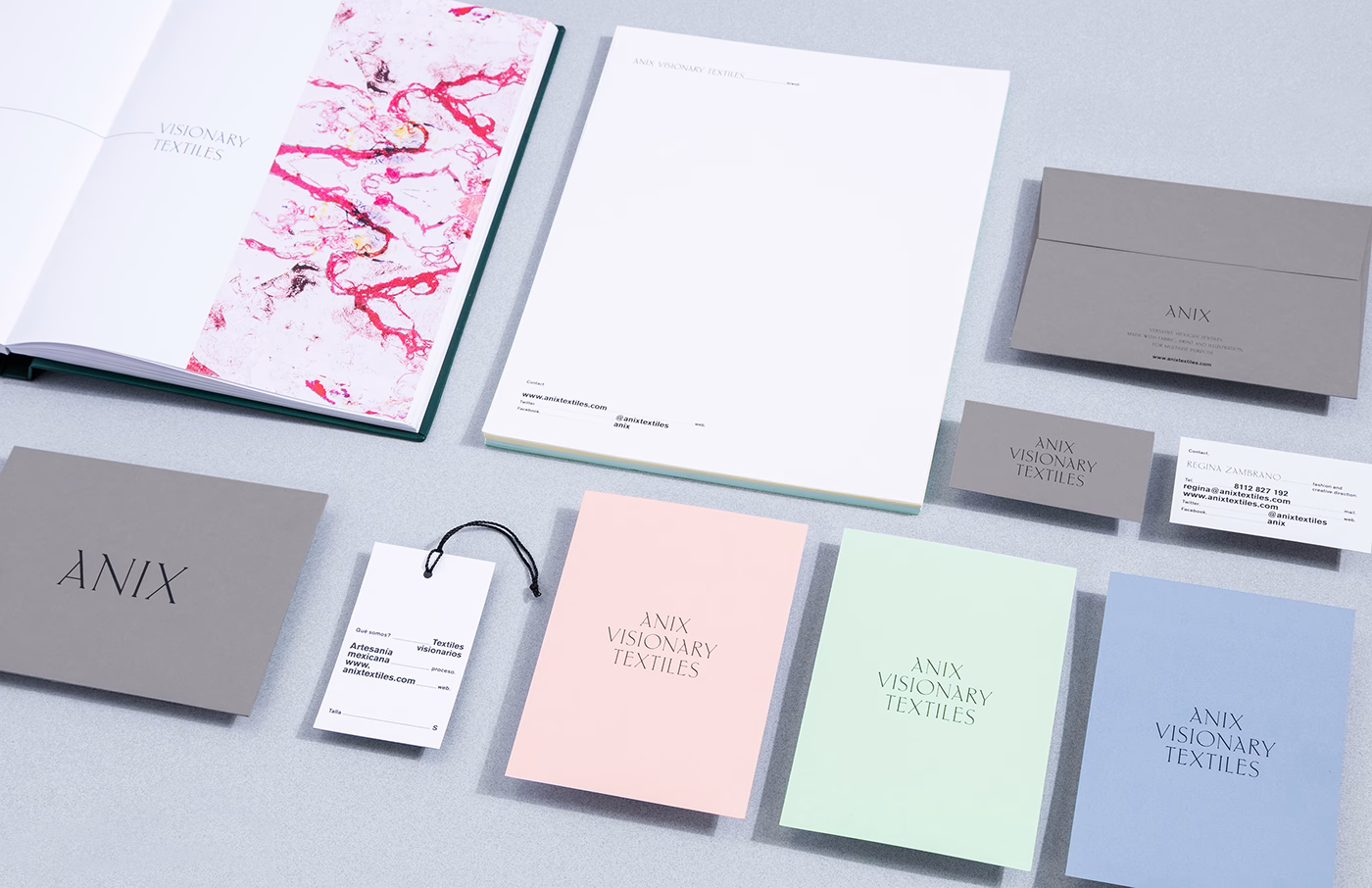 A collection of stationery in soft pastel colors and greys, featuring printed text and a marbled cover design.
