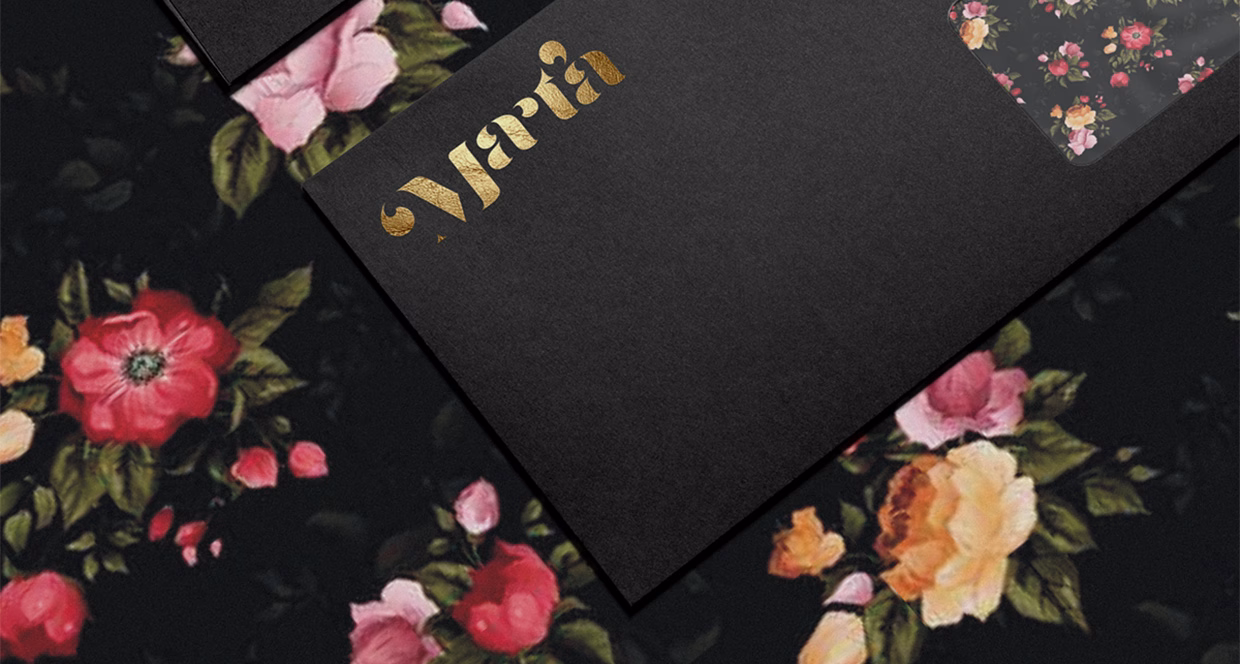 A black card with gold lettering overlays a floral pattern featuring pink and orange blooms against a dark background.