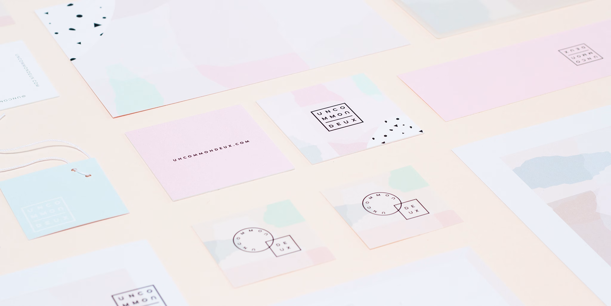 A flat lay of pastel-colored business cards and tags features geometric patterns and varying shapes on a light background.