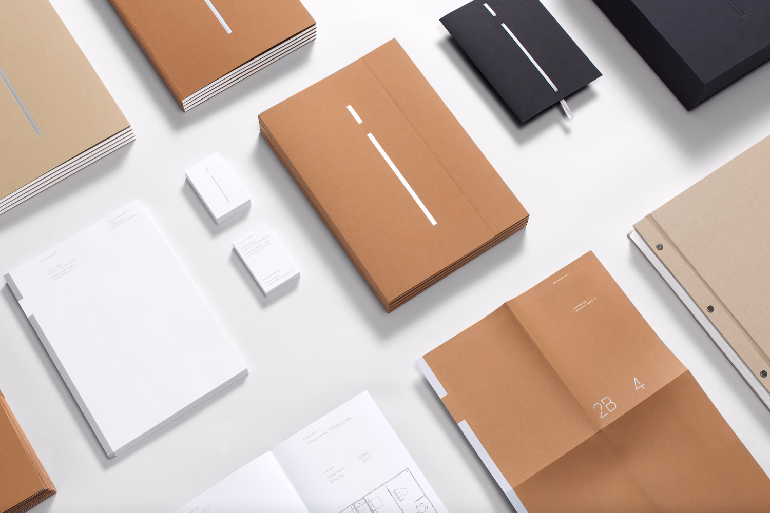 An arrangement of papers and notebooks in earthy tones, featuring minimalistic designs and clean typography.