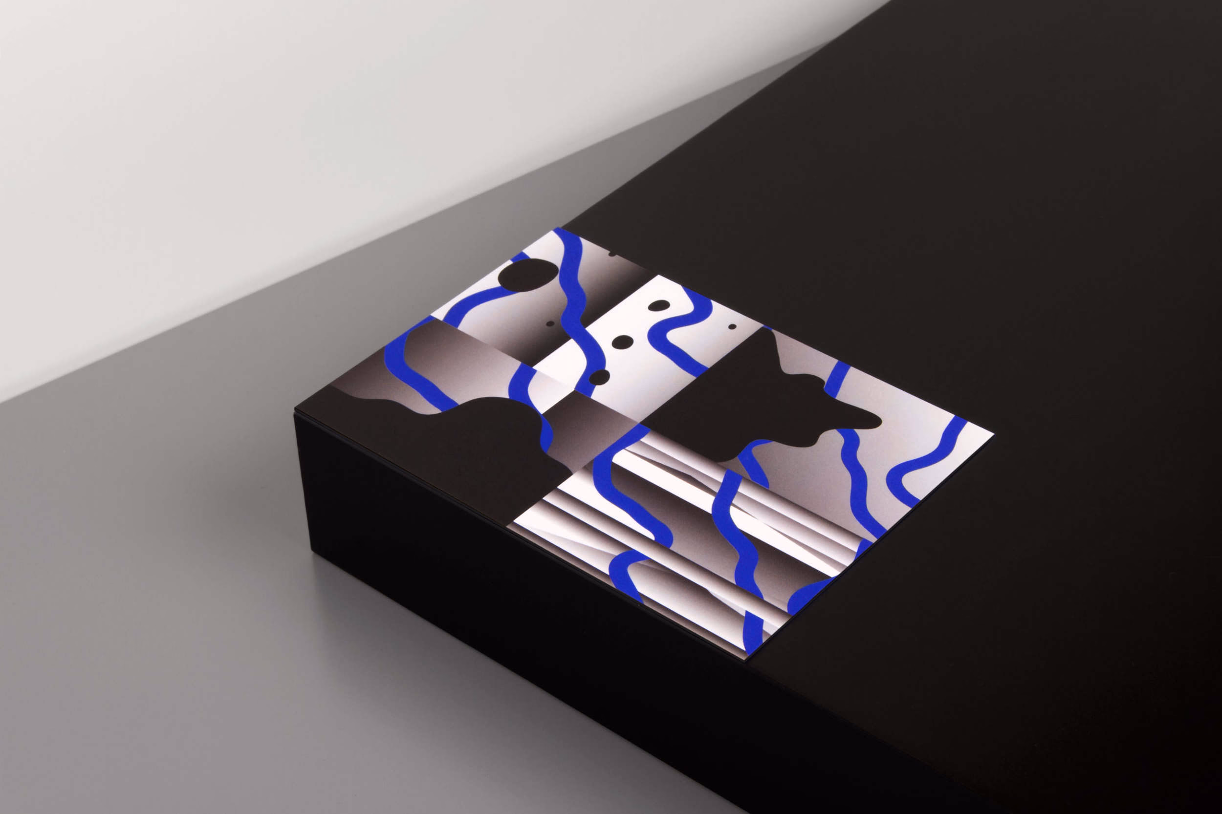 A black box with a colorful abstract design featuring blue lines and geometric shapes on the lid.