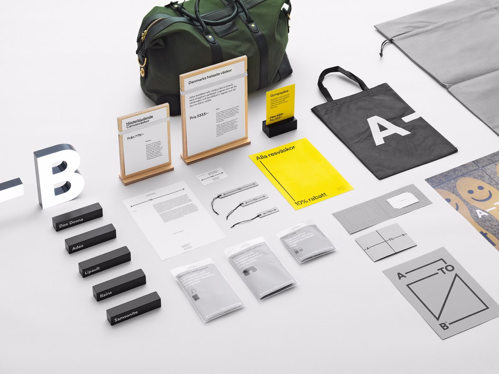 A collection of branded items includes a green bag, a black tote, and various printed materials on a white surface.