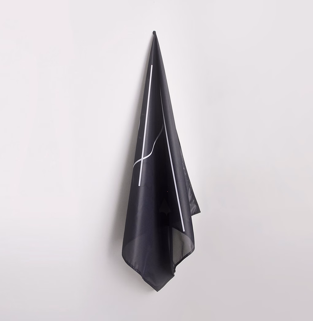 A black fabric hangs elegantly on a wall, featuring a simple white line design that adds a modern touch.