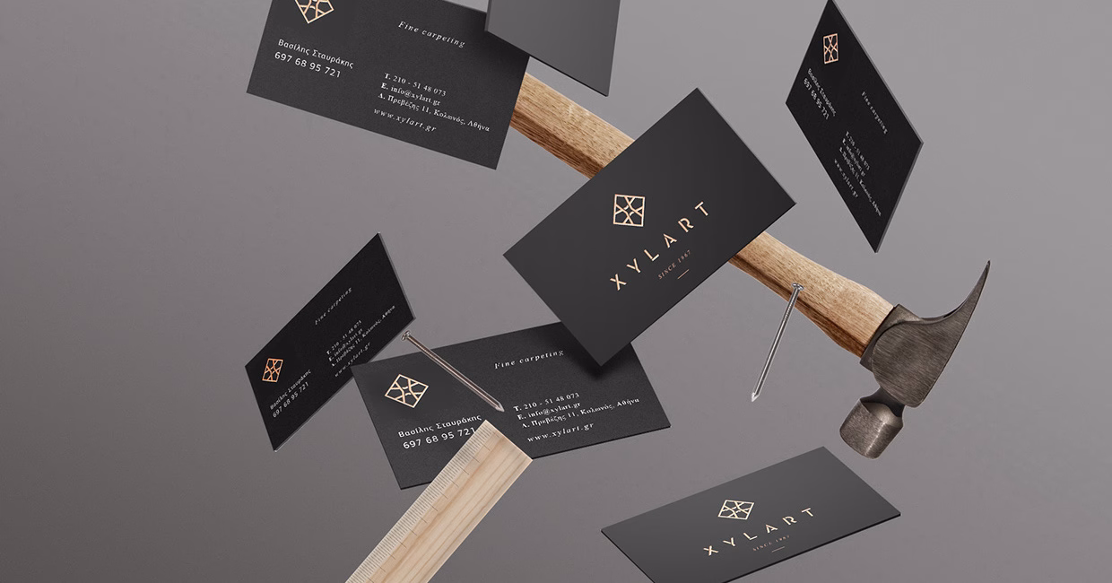 A hammer rests on a wooden ruler, surrounded by floating black business cards featuring gold text and a logo.