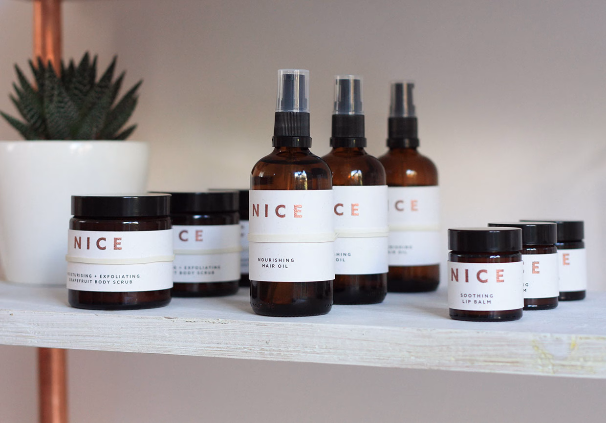 A selection of skincare products with minimalist labels, set against a simple wooden shelf and a potted plant.
