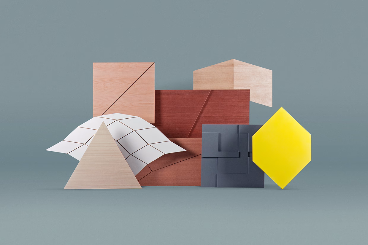 Geometric shapes in wood and paper are arranged artfully, featuring a striking yellow hexagon against a soft green background.