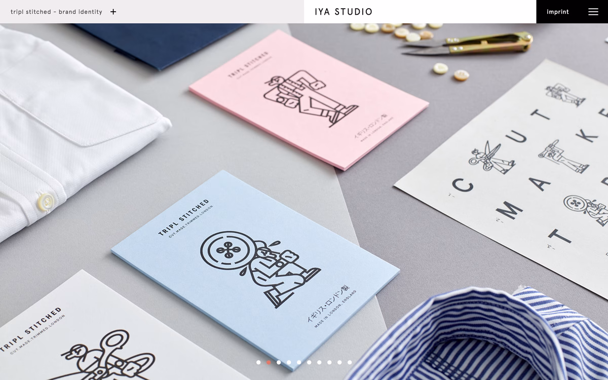 A collection of booklets and fabric in muted colors, laid out alongside sewing tools on a gray background.