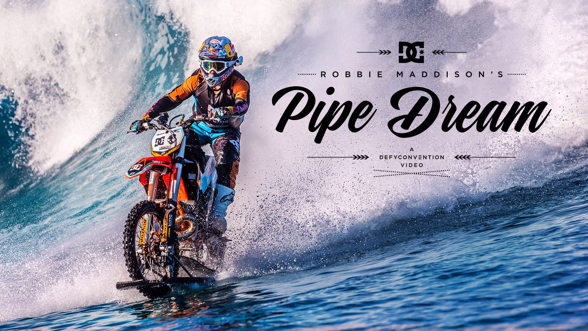 A motorcyclist rides on water, splashing waves against a backdrop of clear blue ocean under a bright sky.