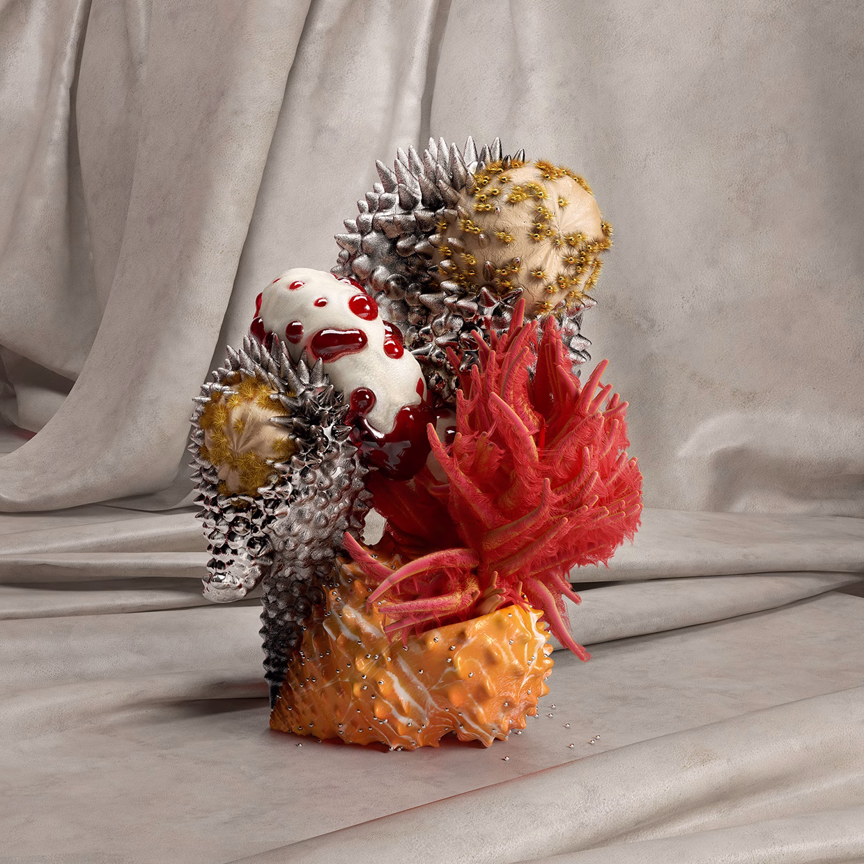 A sculptural arrangement features textured forms in metallic and vibrant red, set against soft, draped fabric.