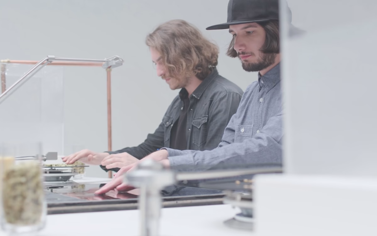Two men, one in a black shirt and the other in a gray button-up, focus on a modern workspace with minimalist design elements.