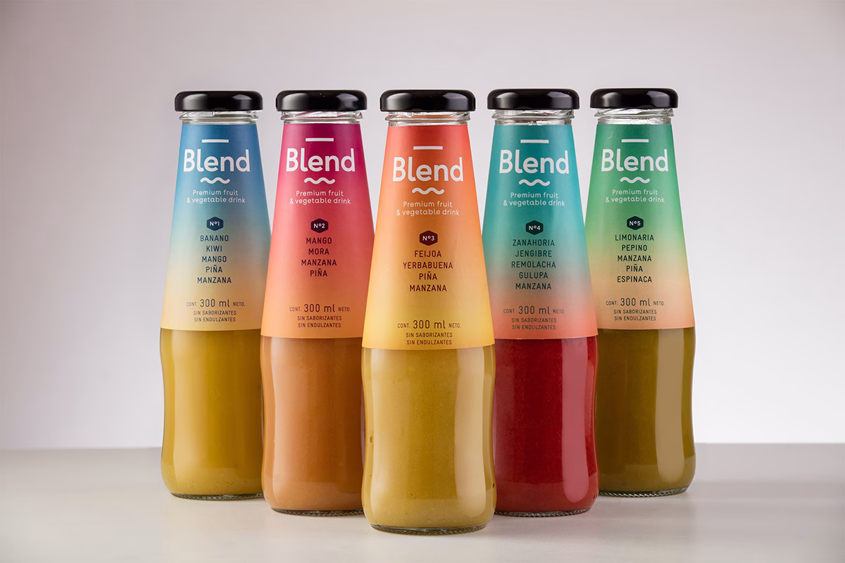 Five glass bottles of fruit and vegetable drinks with gradient-colored labels, arranged neatly on a white surface.