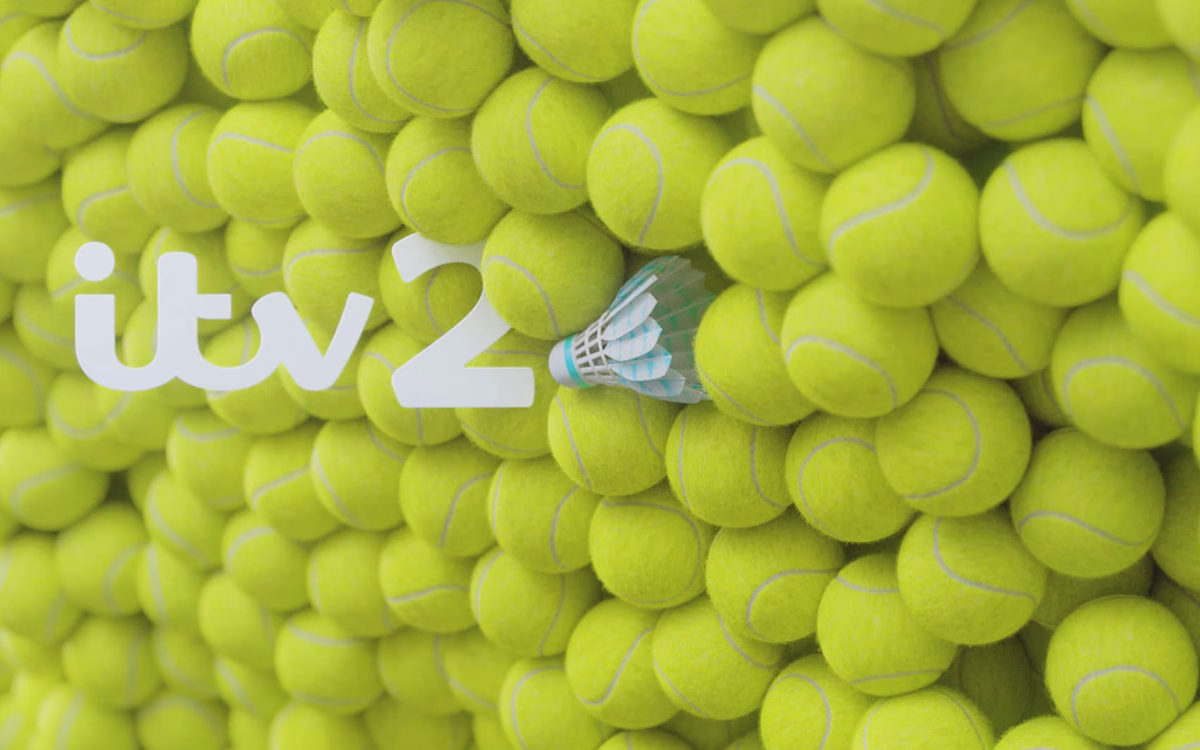 A cluster of bright yellow tennis balls surrounds the white logo "itv2" and a blue and white shuttlecock.