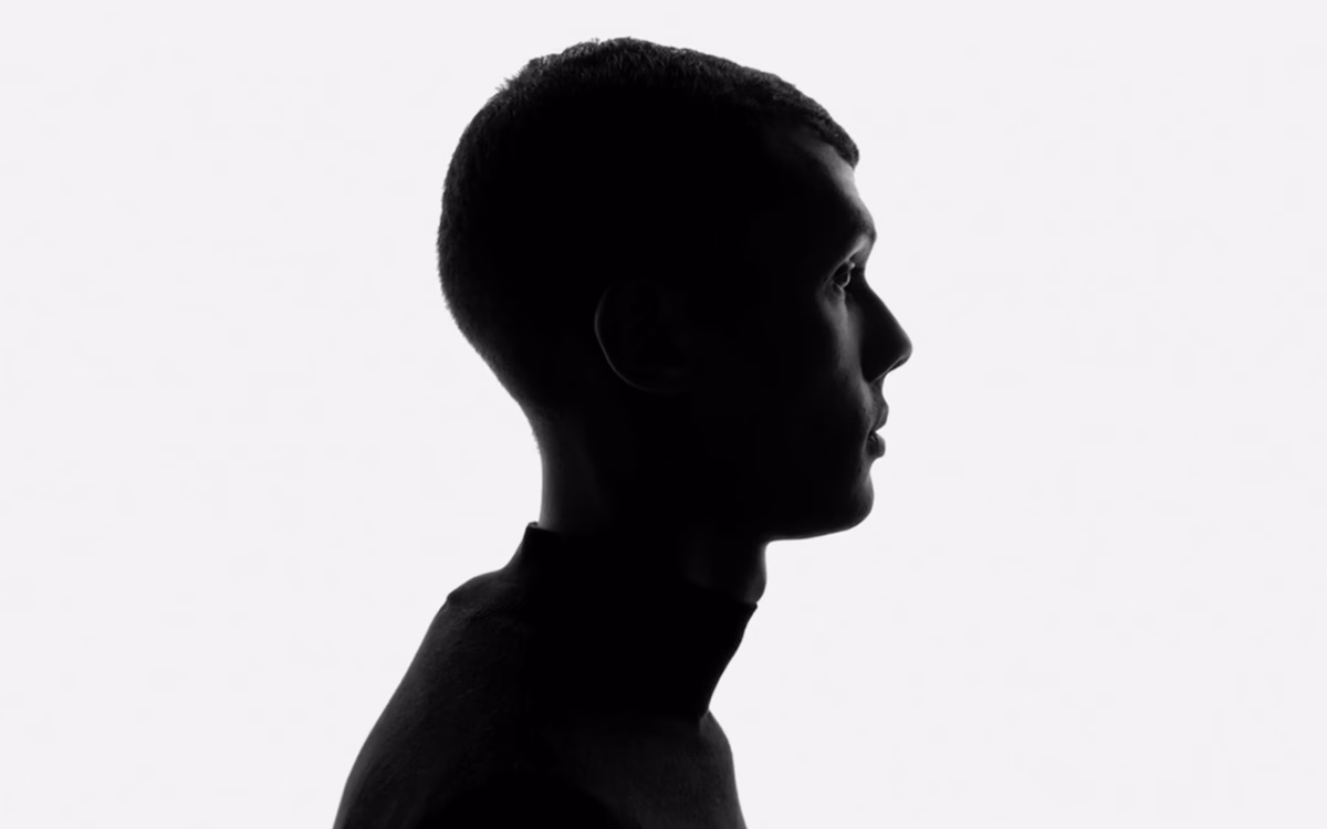 A silhouetted profile of a person wearing a black turtleneck against a bright white background.