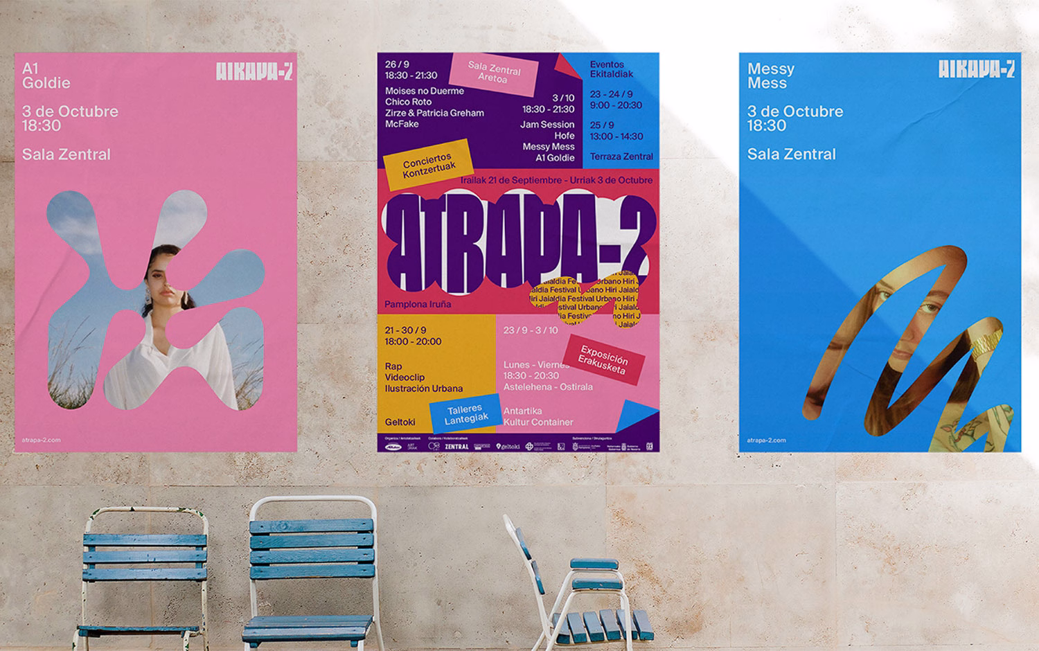 Three colorful event posters in pink, purple, and blue are displayed on a textured wall above two blue and white chairs.